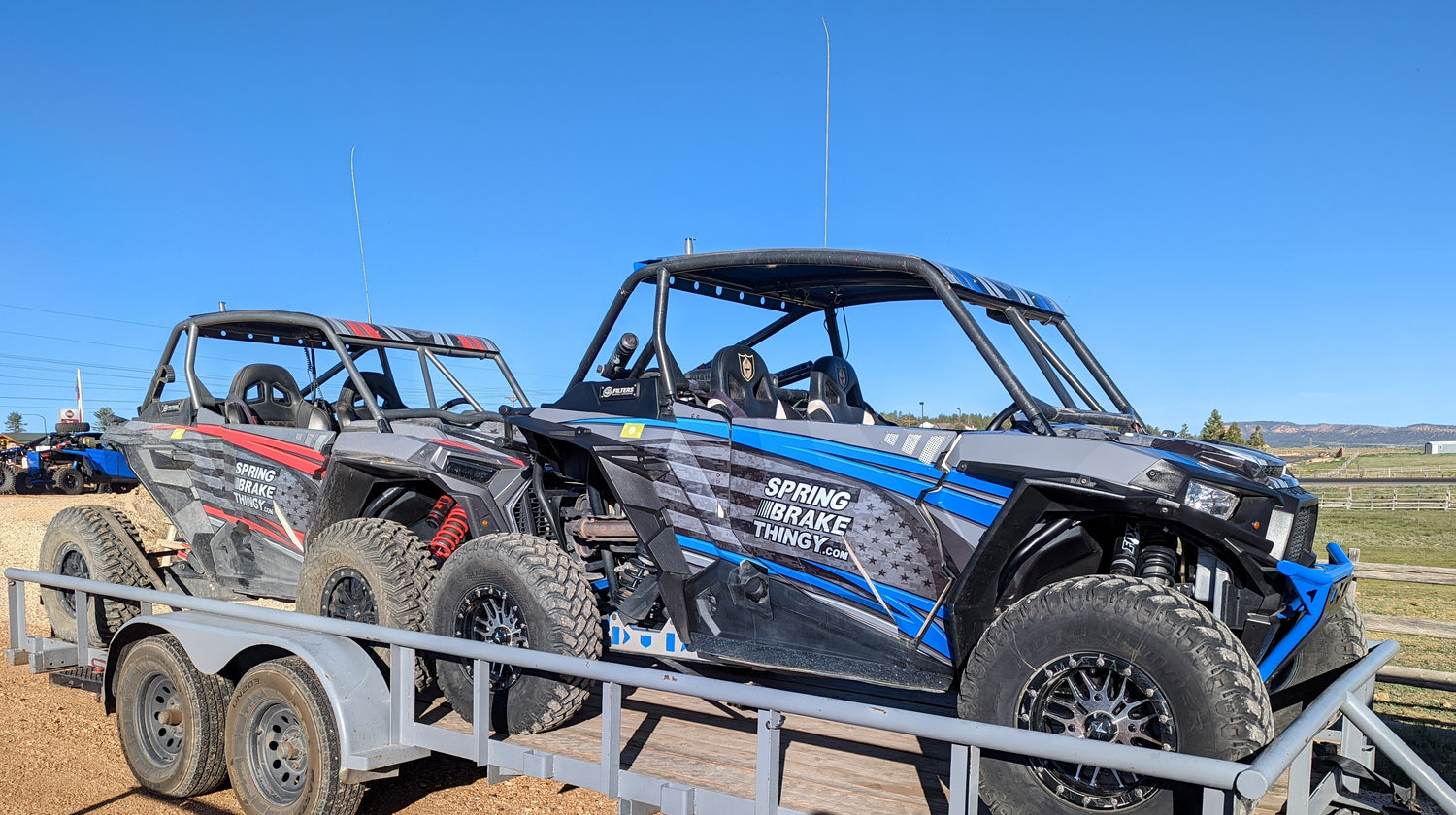 two rzr's on a trailer with the spring brake thingy parking brake set